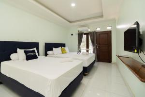 a hotel room with two beds and a tv at Urbanview Hotel Kampung Istal Megamendung Puncak by RedDoorz in Cipayung