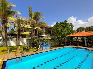 ein Pool vor einem Haus mit Palmen in der Unterkunft Pearl Island Beach Hotel in Hikkaduwa