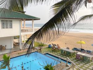 a house with a swimming pool next to the beach at Pearl Island Beach Hotel in Hikkaduwa