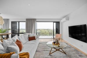 a living room with a couch and a tv at Peninsula Hot Springs Designer Home in Fingal