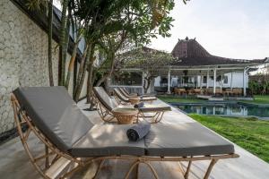 a patio with chairs and a table and a pool at Isaiya Boutique Hotel in Canggu