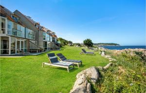 a house with two chairs on the grass next to the ocean at Amazing Apartment In Allinge With Kitchen in Sandvig