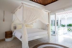 a bedroom with a white bed with a canopy at Isaiya Boutique Hotel in Canggu