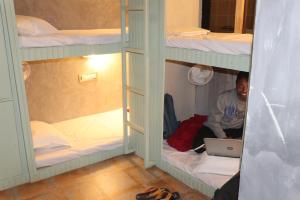 a man sitting on a bunk bed with a laptop at Bunkyard Hostel in Udaipur