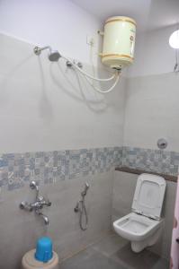 a bathroom with a toilet and a bucket on the wall at J C Comforts in Bangalore