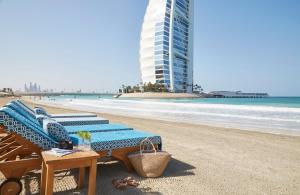a beach with two lounge chairs and a building at Jumeirah Beach Hotel in Dubai
