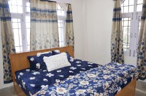 a bedroom with a bed with a blue and white comforter and windows at Three bedroom house with private garden in Solan