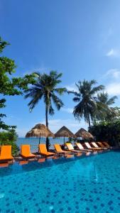 - une piscine avec chaises longues et parasols et l'océan dans l'établissement Serenity Resort Koh Chang, à Ko Chang