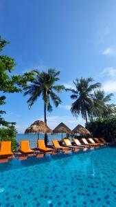 una piscina con sillas y sombrillas y el océano en Serenity Resort Koh Chang en Ko Chang