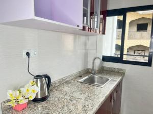 a kitchen counter with a sink and a vase of flowers at Appartement somptueux à Kotto in Douala
