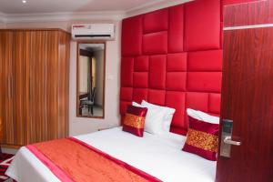 a bedroom with a large bed with a red headboard at Golden Tulip Garden City Hotel - Rivotel in Port Harcourt