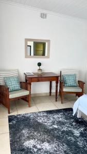 a bedroom with a desk and two chairs and a mirror at Sail Away Studios in Simonʼs Town