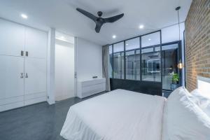 ein Schlafzimmer mit einem weißen Bett und einem Deckenventilator in der Unterkunft Loft Ludo 8 - Superb 1-bdr luxury loft in Great Location! in Canggu