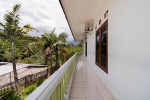 a balcony of a house with palm trees at Urbanview Hotel Kampung Istal Megamendung Puncak by RedDoorz in Cipayung