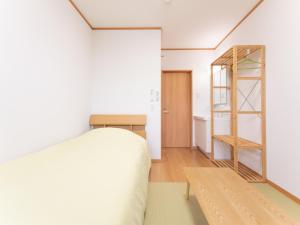 1 dormitorio con cama y estante de madera en Hirononomori Maehama Bekkan Male Only, en Hirono