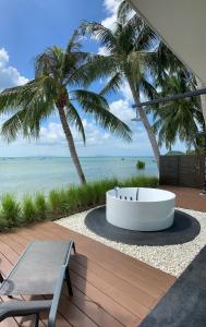 a bath tub sitting on a beach with palm trees at Villa Mandi in Ban Thong Phlu