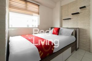 1 dormitorio con 1 cama con almohadas blancas y rojas en RedLiving Apartemen Kalibata City - SAG Property Tower Kemuning, en Yakarta
