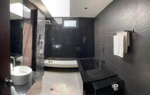 Baño negro con bañera y lavamanos en Villa Mandi, en Ban Thong Phlu