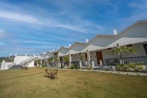 una fila de casas blancas con sillas en un patio en Yellow Tail by Puggles Resorts, en Rāmnagar