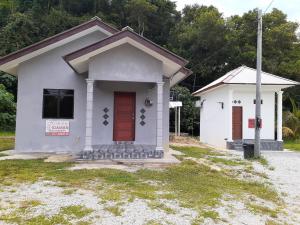 una pequeña casa blanca con una puerta roja en Homestay & Roomstay Bukit Berapit, en Kuala Terengganu