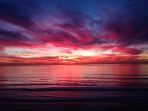 a sunset on the beach with a red at Leucadia Beach Inn in Encinitas