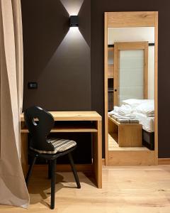 a bedroom with a desk and a chair next to a bed at Hotel Rech-Hof Sayonara in Folgaria