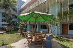 Urbanview Hotel Kebayoran Baru Blok S في جاكرتا: طاولة مع مظلة خضراء في ساحة الفناء