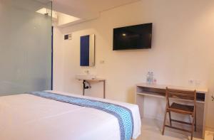 1 dormitorio con 1 cama y escritorio con TV en la pared en Little Mykonos, en Bandung