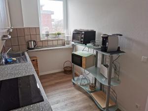 une cuisine avec deux étagères et un four micro-ondes. dans l'établissement FeWo Jadeblick - Horumersiel, à Horumersiel