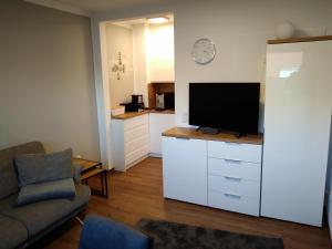 ein Wohnzimmer mit einem TV auf einer weißen Kommode in der Unterkunft FeWo Kleine Freiheit mit Balkon - Horumersiel in Horumersiel