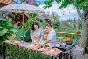 un hombre y una mujer preparando comida en una mesa en Nur Guest House by Purely en Ubud