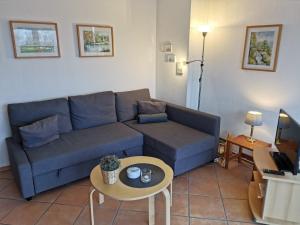 een woonkamer met een blauwe bank en een tafel bij FeWo Jadekieker mit Balkon - Horumersiel in Horumersiel