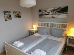 een slaapkamer met een bed met 2 nachtkastjes en 2 lampen bij FeWo Jadekieker mit Balkon - Horumersiel in Horumersiel