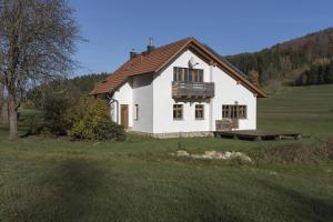 una casa bianca con una panchina in un campo di Ruhe-haus a Grafenau