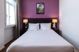 um quarto com uma grande cama branca com paredes roxas em Hôtel Le Mondon em Metz