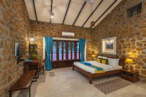 een slaapkamer met een bed en een stenen muur bij SaffronStays Lake House Bouganvillea, Nashik - rustic pool villa with great lake views and patio dining in Nashik