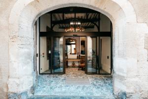 un arco que conduce a una habitación con una mesa en Le Clos Violette et Le 11 D'Aglaé - Appart' hôtel Design de Luxe en LʼIsle-sur-la-Sorgue