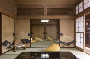a room with two beds and a chair and windows at Jokan-en in Honjo