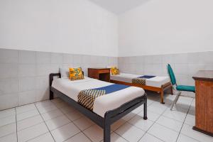 a room with two beds and a desk and a chair at SPOT ON Sartika Inn Pati in Pati