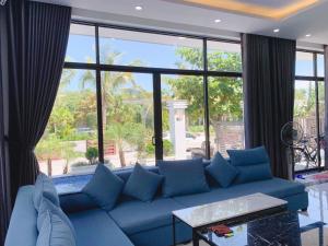 um sofá azul numa sala de estar com uma grande janela em Villa FLC Sầm Sơn Vị Trí Trung Tâm View Biển em Sam Son