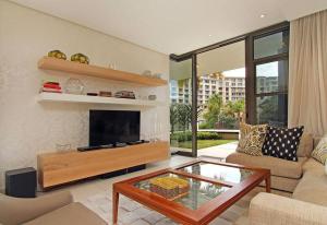 sala de estar con TV, sofá y mesa en Luxury Villa in V&A Waterfront, en Ciudad del Cabo