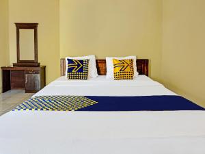 a bed with blue and yellow pillows on it at OYO 91988 Azka Homestay Klayar in Pacitan