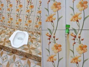 a bathroom with a toilet on the wall with flowers at OYO 91988 Azka Homestay Klayar in Pacitan