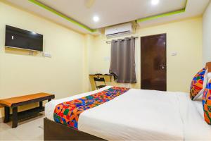 a bedroom with a bed and a table and a television at FabExpress Broholic Suites in Hyderabad