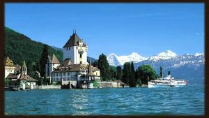 eine kleine Stadt auf einem See mit einem Schloss und einem Boot in der Unterkunft Schwendi-Blueme in Heiligenschwendi