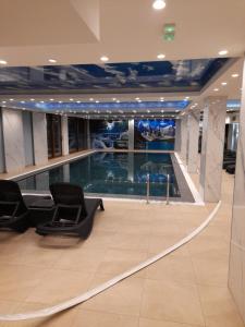 een groot zwembad in een gebouw met stoelen bij President Kop - Apartman A21 in Kopaonik