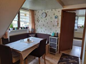 a dining room with a table and chairs and a clock on the wall at Ferienwohnung Sonja mit Garten und Freisitz in Steinwiesen +4 photos
