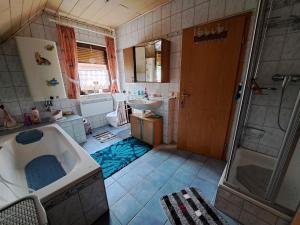 ein Bad mit einer Badewanne, einem Waschbecken und einer Dusche in der Unterkunft Ferienwohnung Sonja mit Garten und Freisitz in Steinwiesen