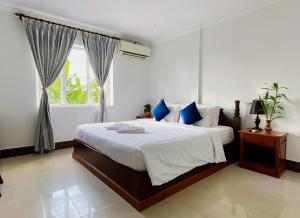 una camera da letto con un letto con cuscini blu e una finestra di The Blanc Residence a Siem Reap