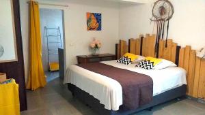 - une chambre avec un grand lit et une tête de lit en bois dans l'établissement CHAMBRES LEZARD Home, à Païta